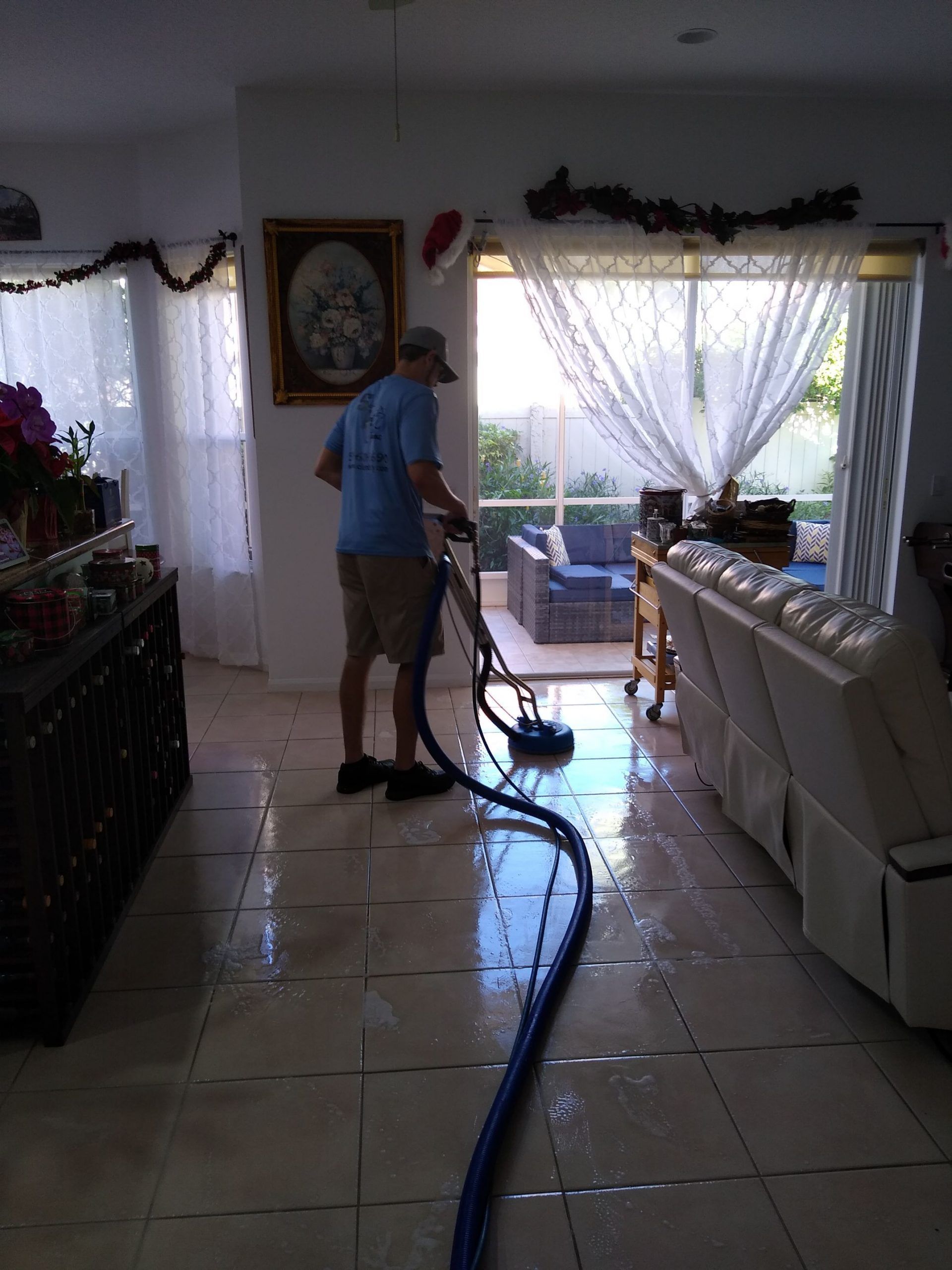 A man is cleaning the floor of a living room with a vacuum cleaner.