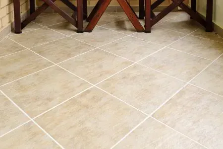 A tiled floor with a wooden table in the background.