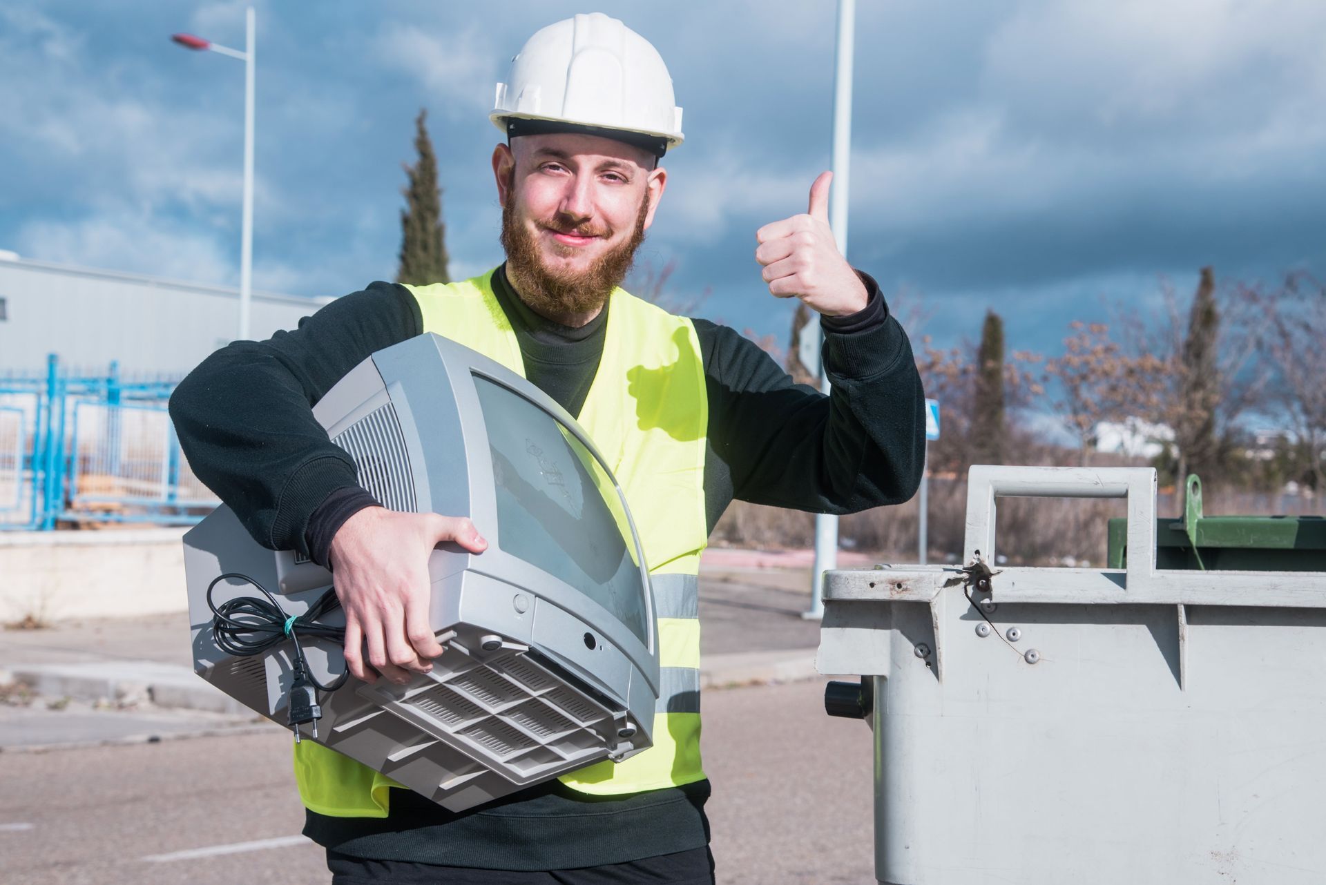 Construction worker in a hard hat and safety vest holding a large metal vent outdoors, giving a thumbs-up