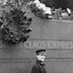 A black and white photo of a man standing in front of a santa claus express sign.