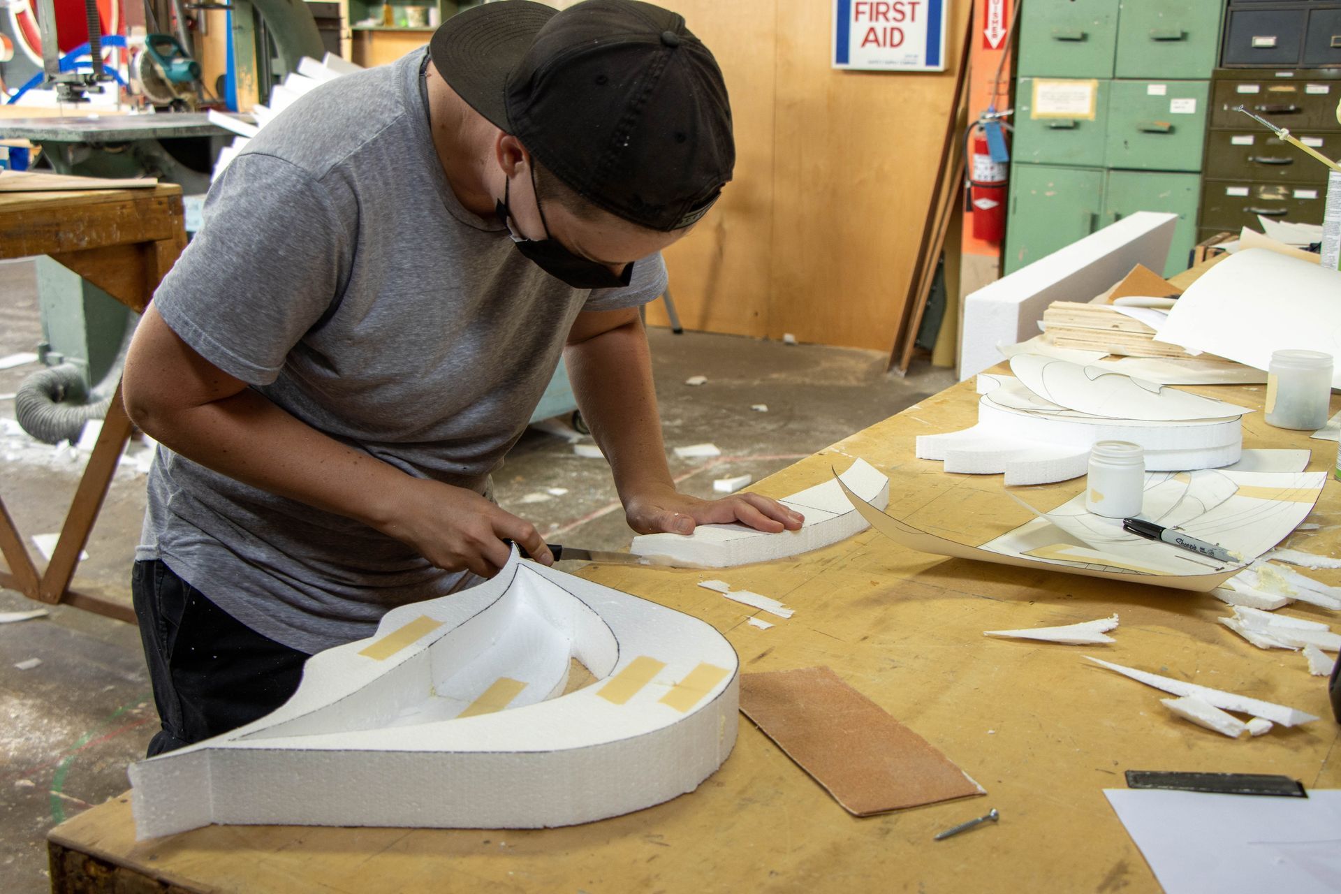 A man wearing a mask is working on a piece of styrofoam.