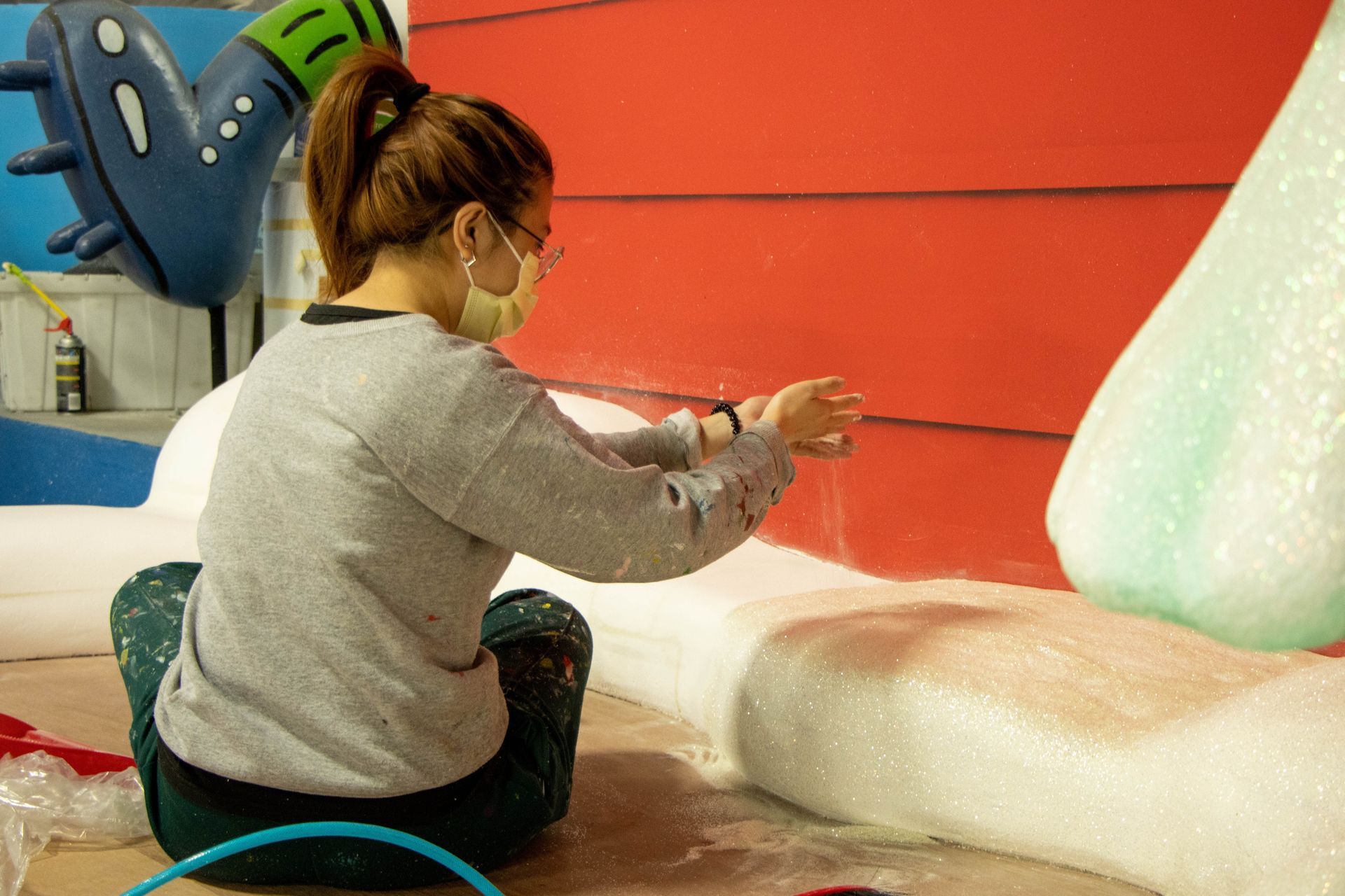 A woman is sitting on the floor painting a sculpture.