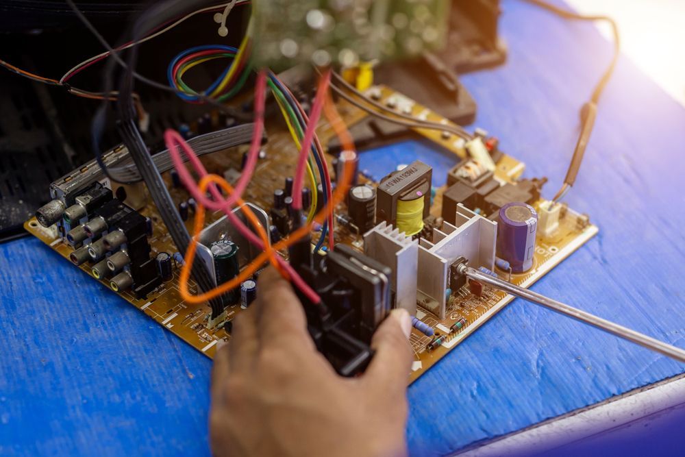 Technician repairing a television on work table - Antenna Services in West Gosford, NSW