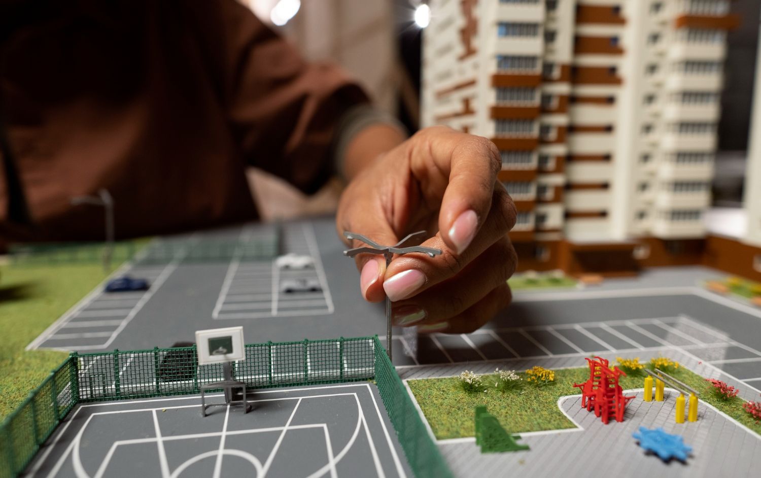 A person is working on a model of a basketball court.