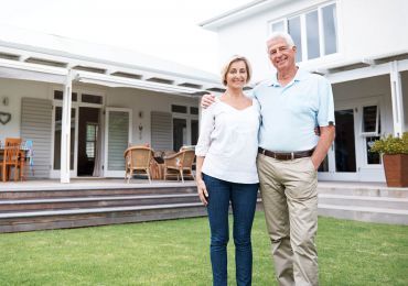 A man and a woman are standing in front of a house.