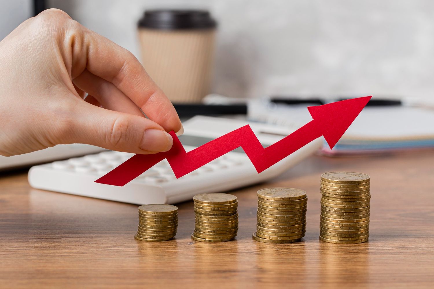 A person is holding a red arrow over stacks of coins.
