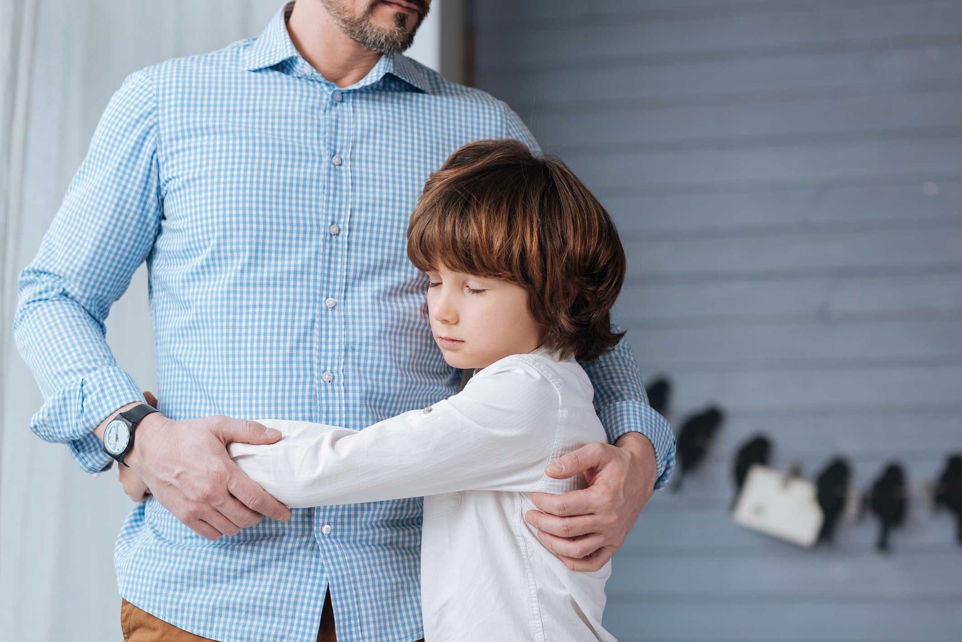 Child hugging a person wearing a navy blue shirt and jeans. The child has a worried expression. Child hugging a person wearing a navy blue shirt and jeans. The child has a worried expression.