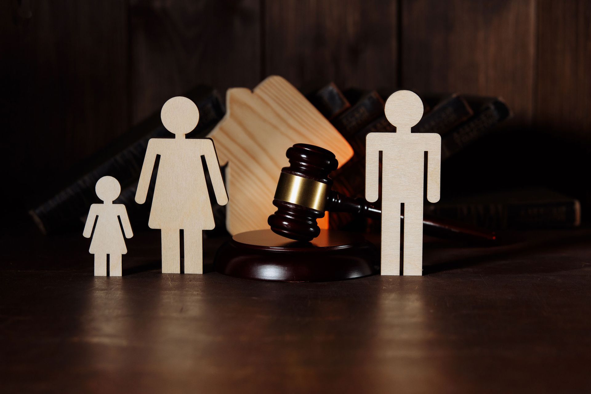 Wooden figures of a family and home with a gavel, symbolizing legal proceedings. Wooden figures of a family and home with a gavel, symbolizing legal proceedings.