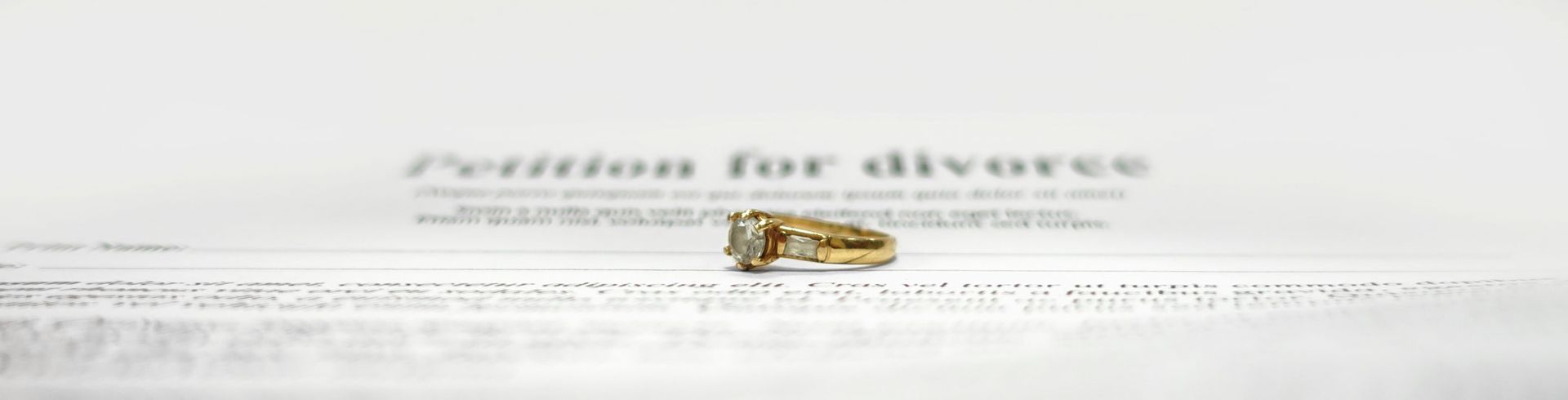 A gold wedding ring sits on a divorce petition. A gold wedding ring sits on a divorce petition.