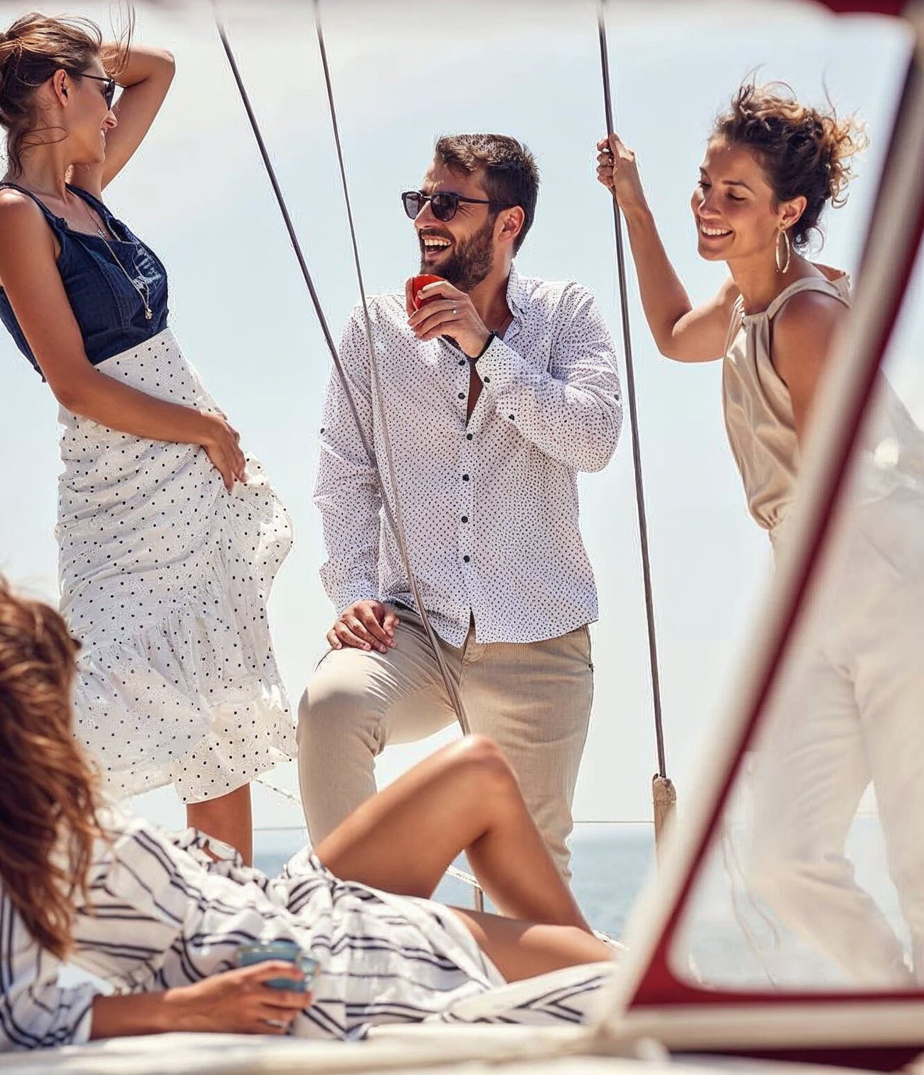 A group jumps off the back of a large white yacht into the ocean, with a blue inflatable slide attached to the side.