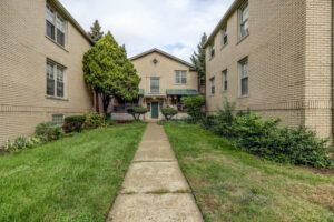 A walkway between two brick buildings with a lush green lawn.