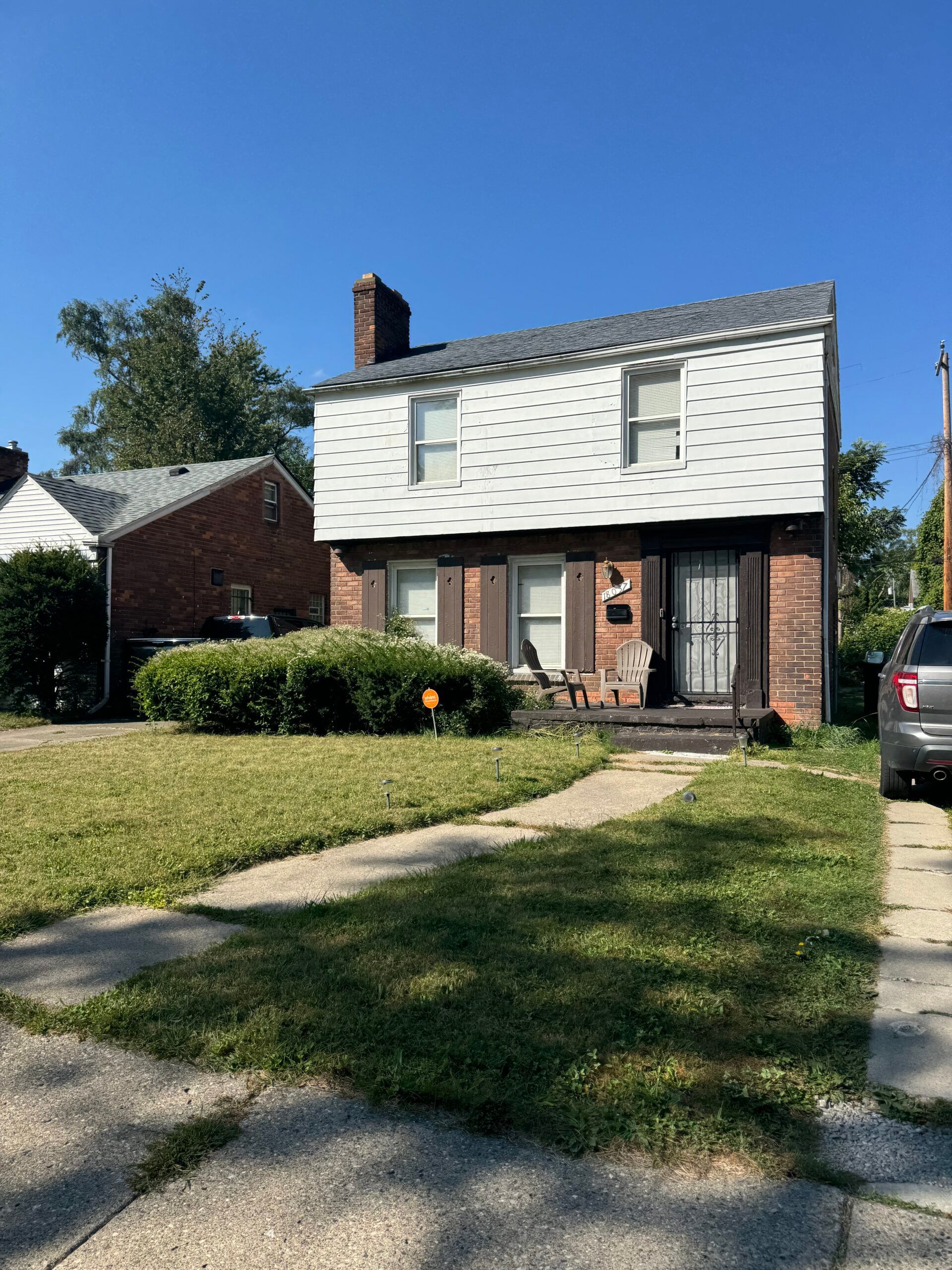 A brick house with a white roof and a car parked in front of it.