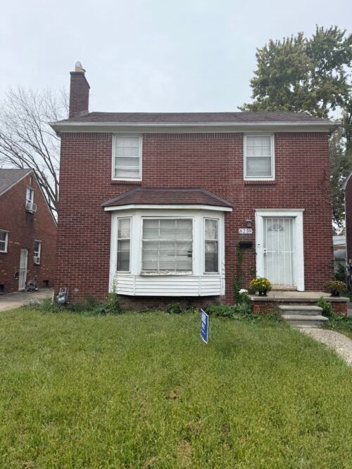 A red brick house with a white door and a bay window.