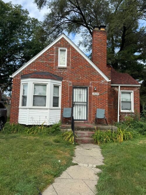 A small brick house with a walkway leading to it and a car parked in front of it.
