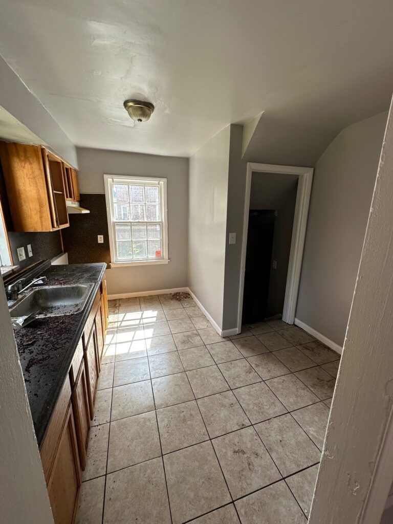 A kitchen with a sink , cabinets , tile floor and a window.