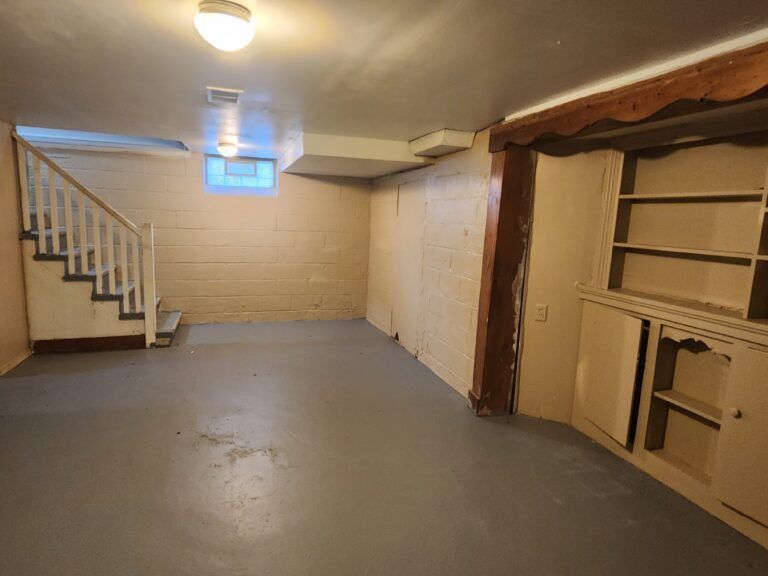 An empty basement with stairs and shelves in it
