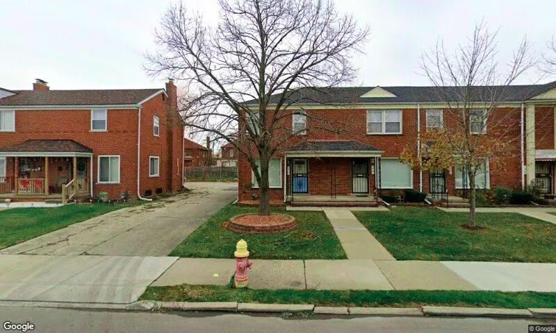 A fire hydrant is in front of a row of brick houses.