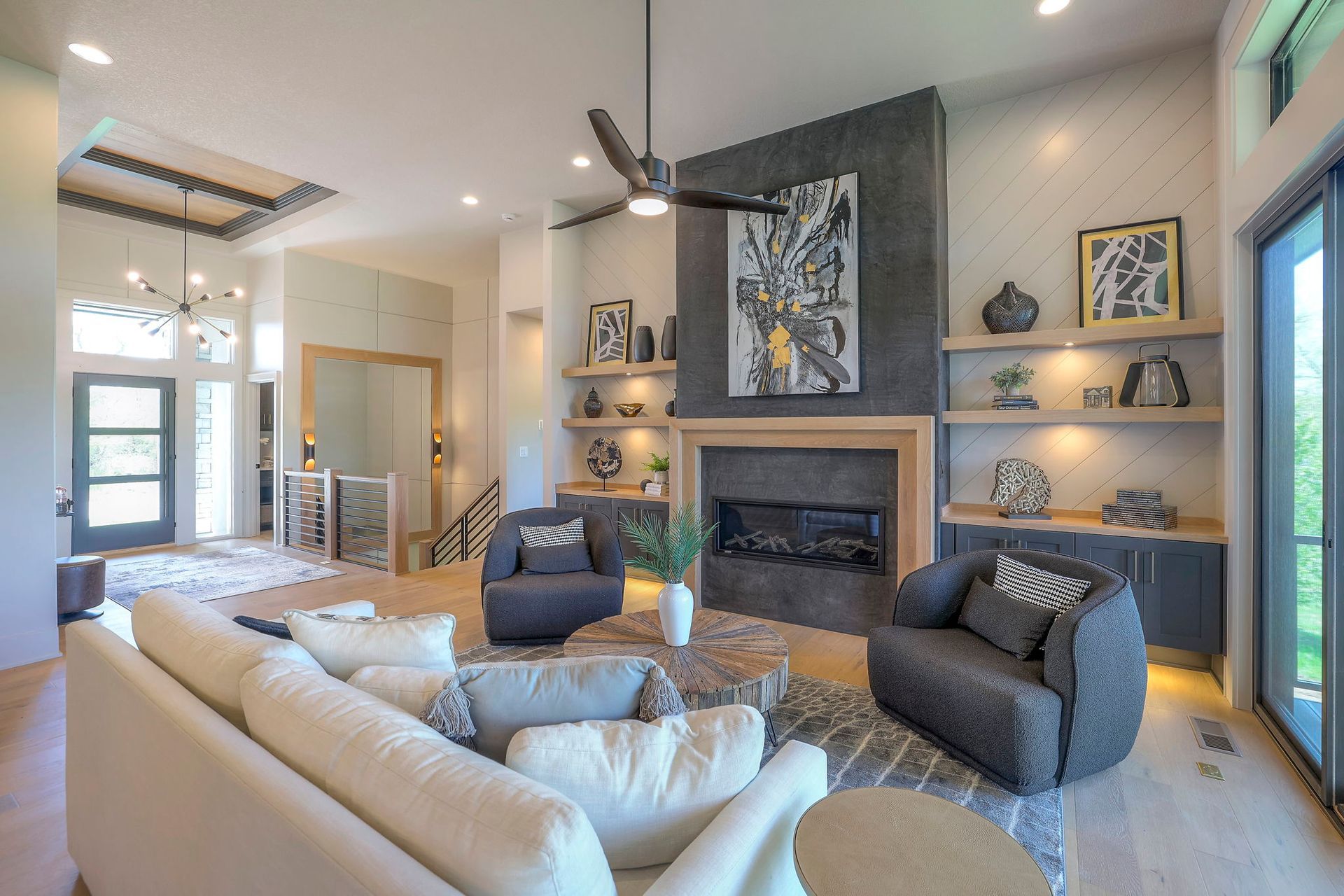 A living room with a couch , chairs , a fireplace and a ceiling fan.