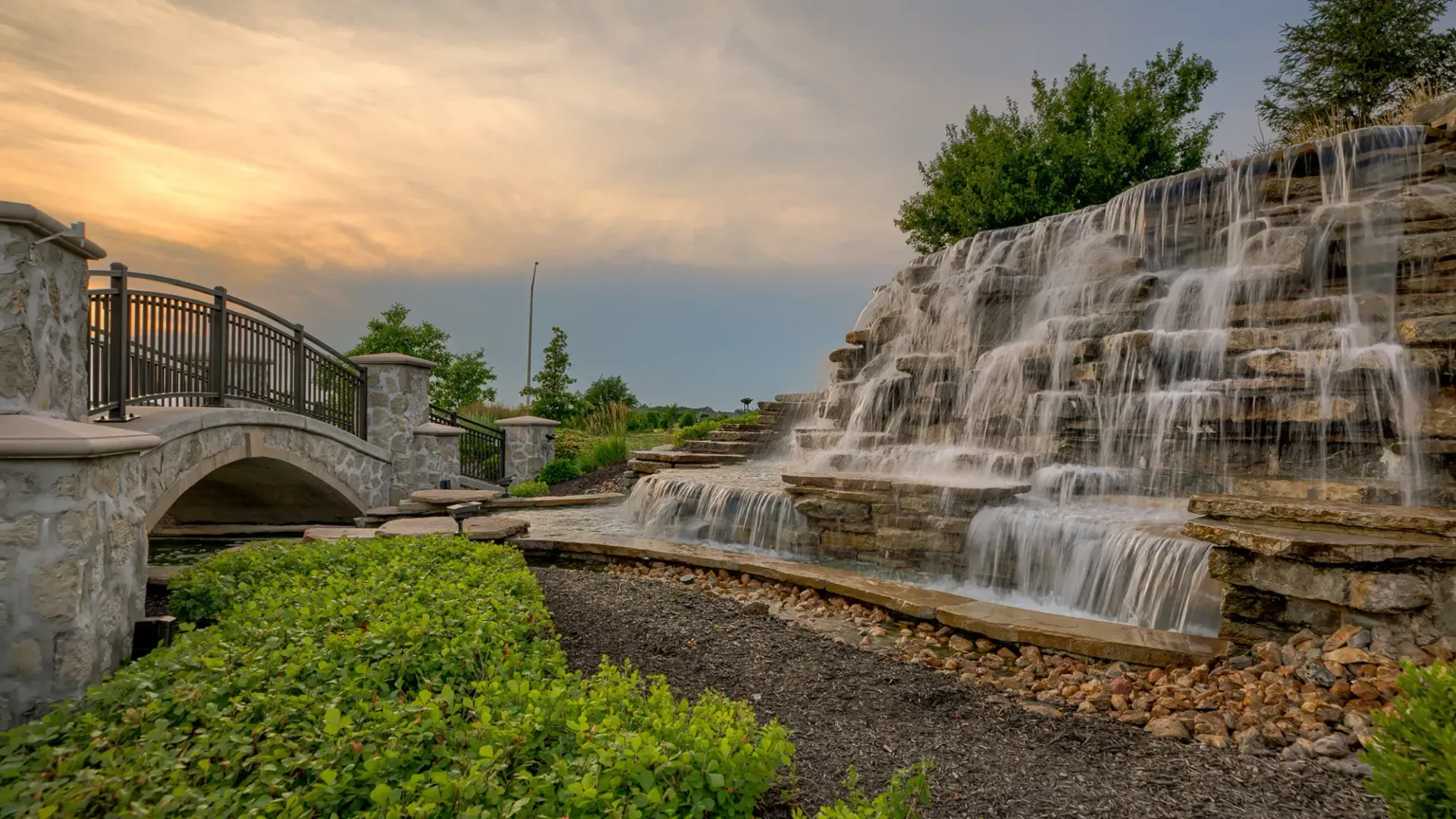 There is a waterfall with a bridge in the background.
