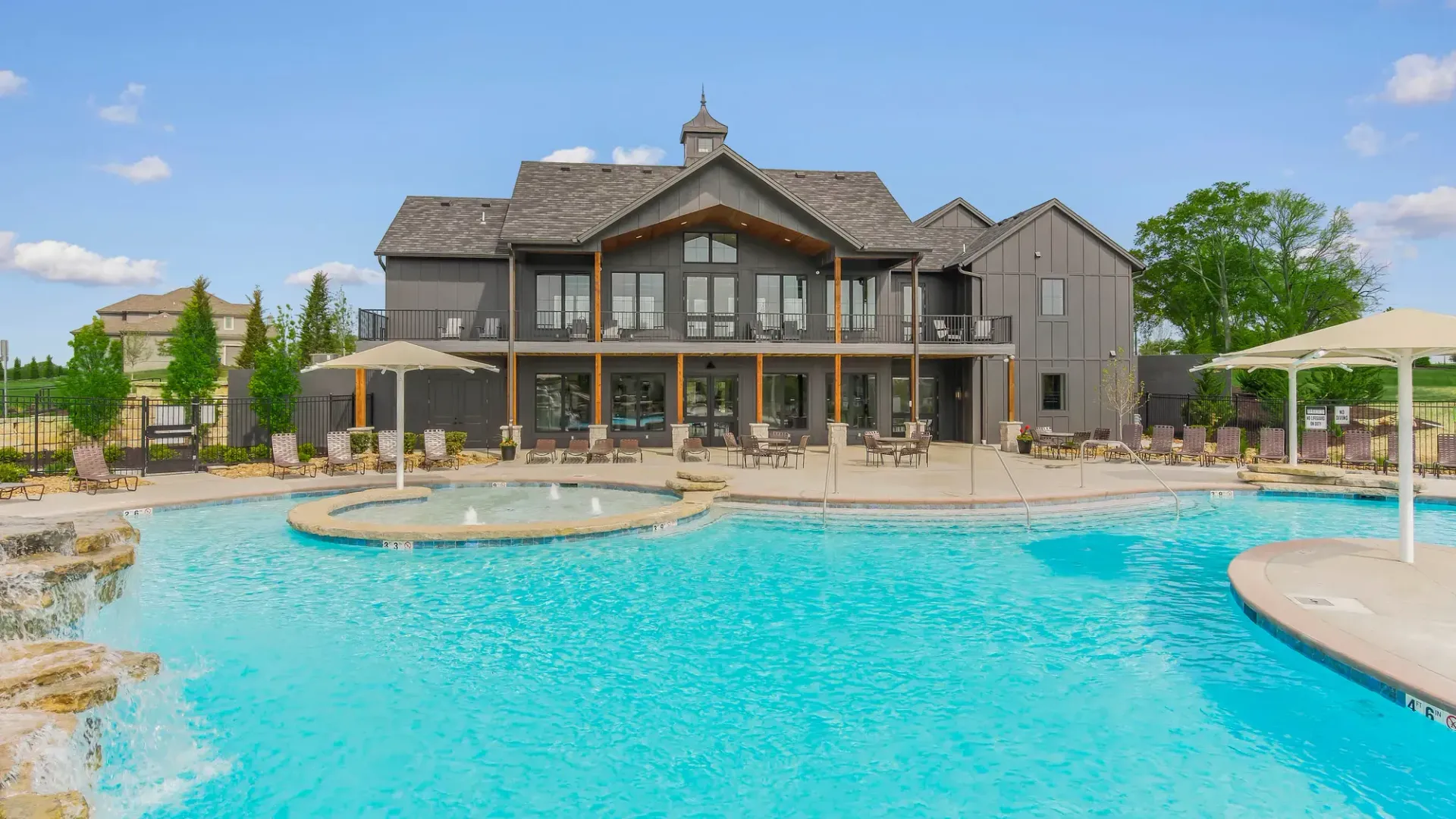 There is a large swimming pool in front of a large house.