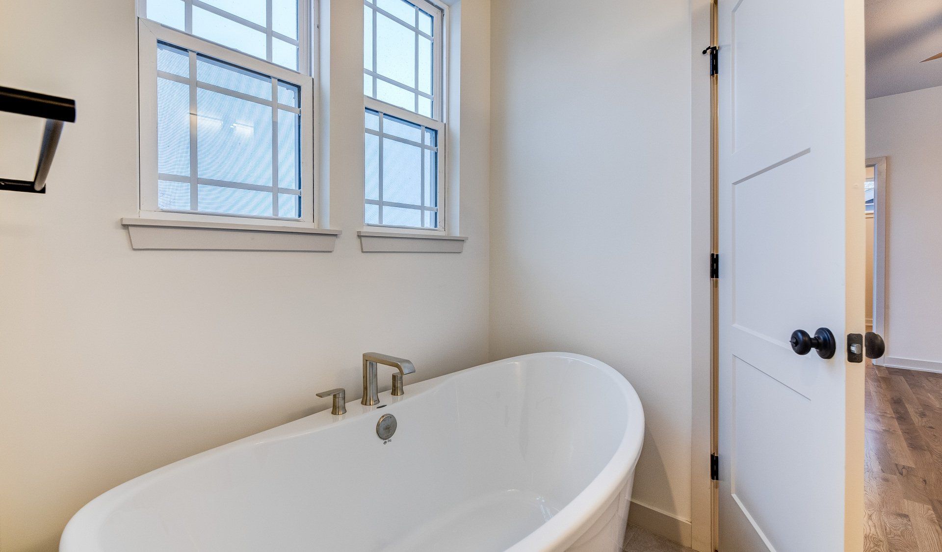 A bathroom with a bathtub and two windows.