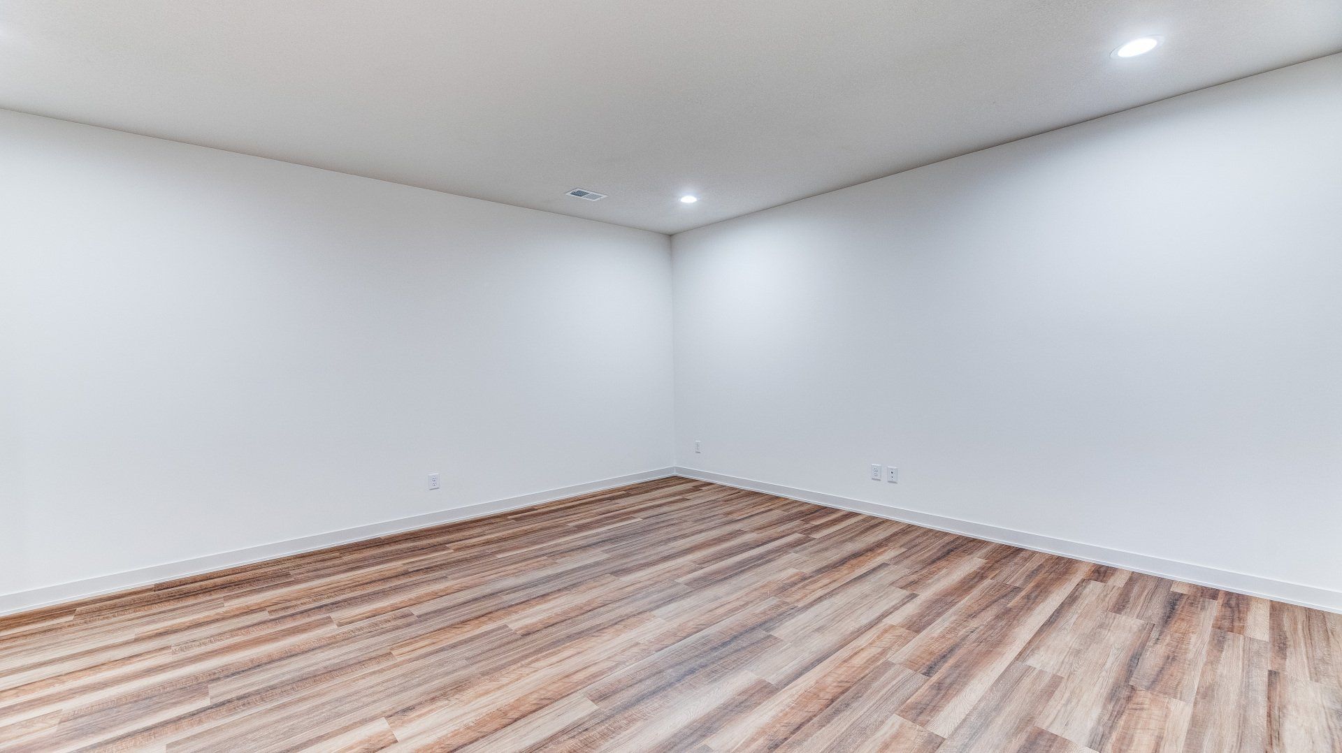 An empty room with wooden floors and white walls.