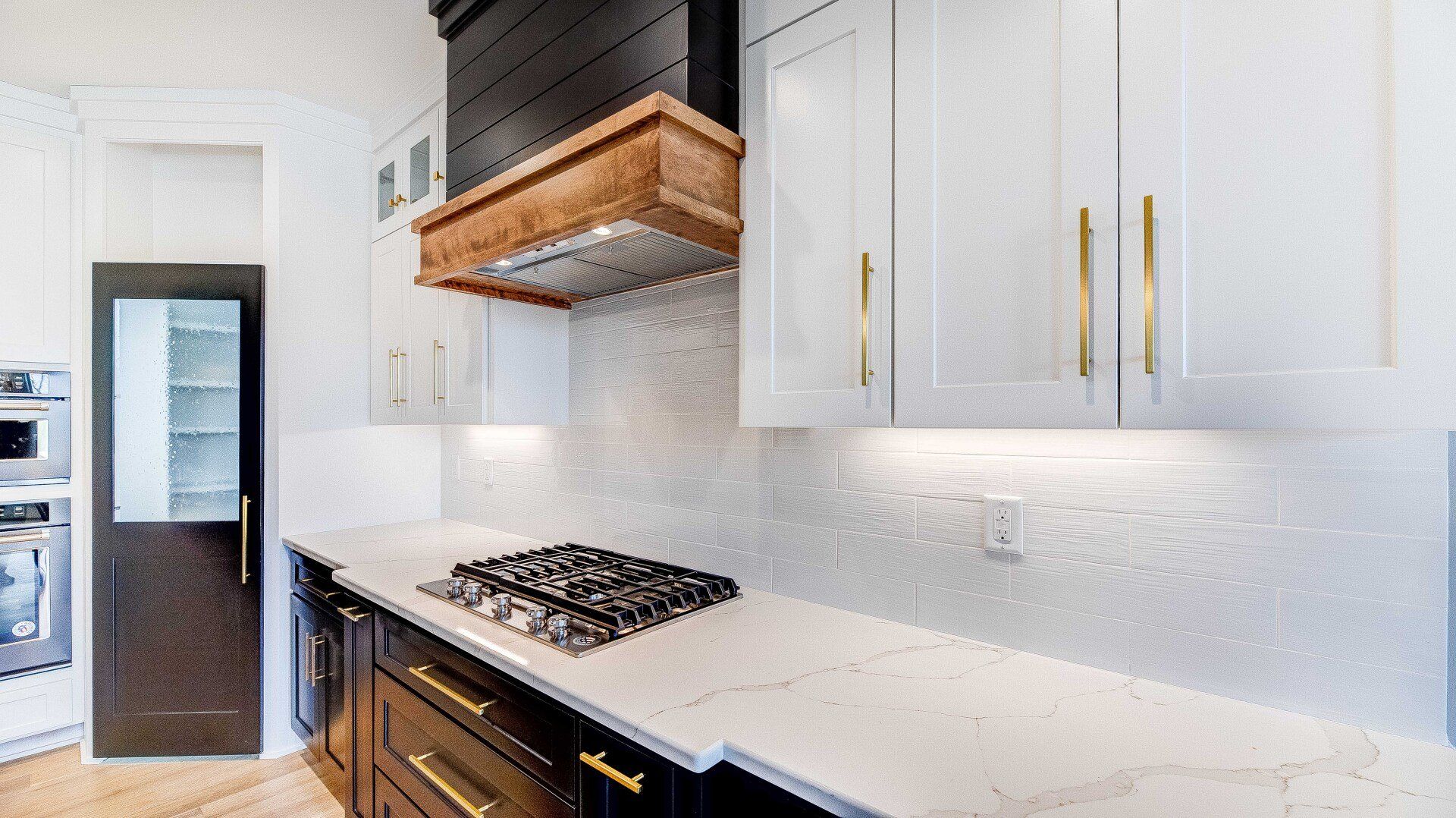 A kitchen with white cabinets , black cabinets , and a stove top oven.