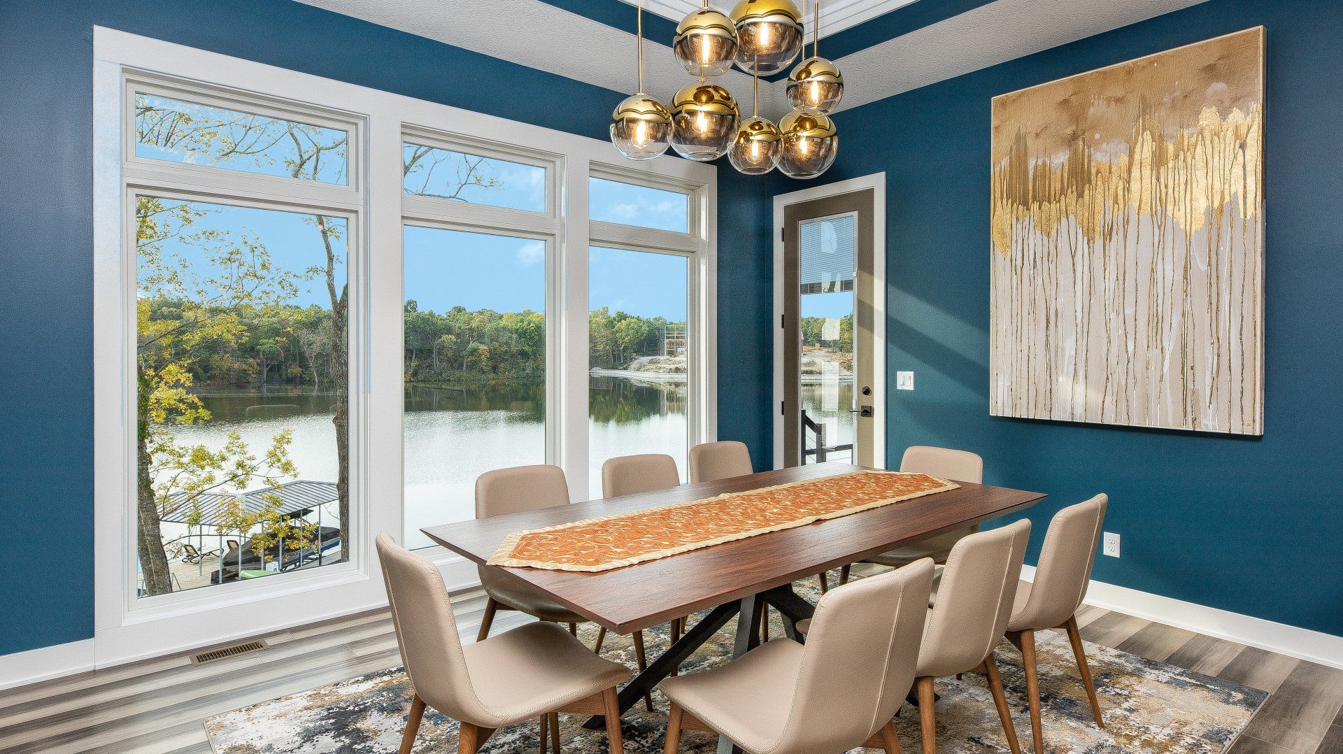 A dining room with a table and chairs and a painting on the wall.