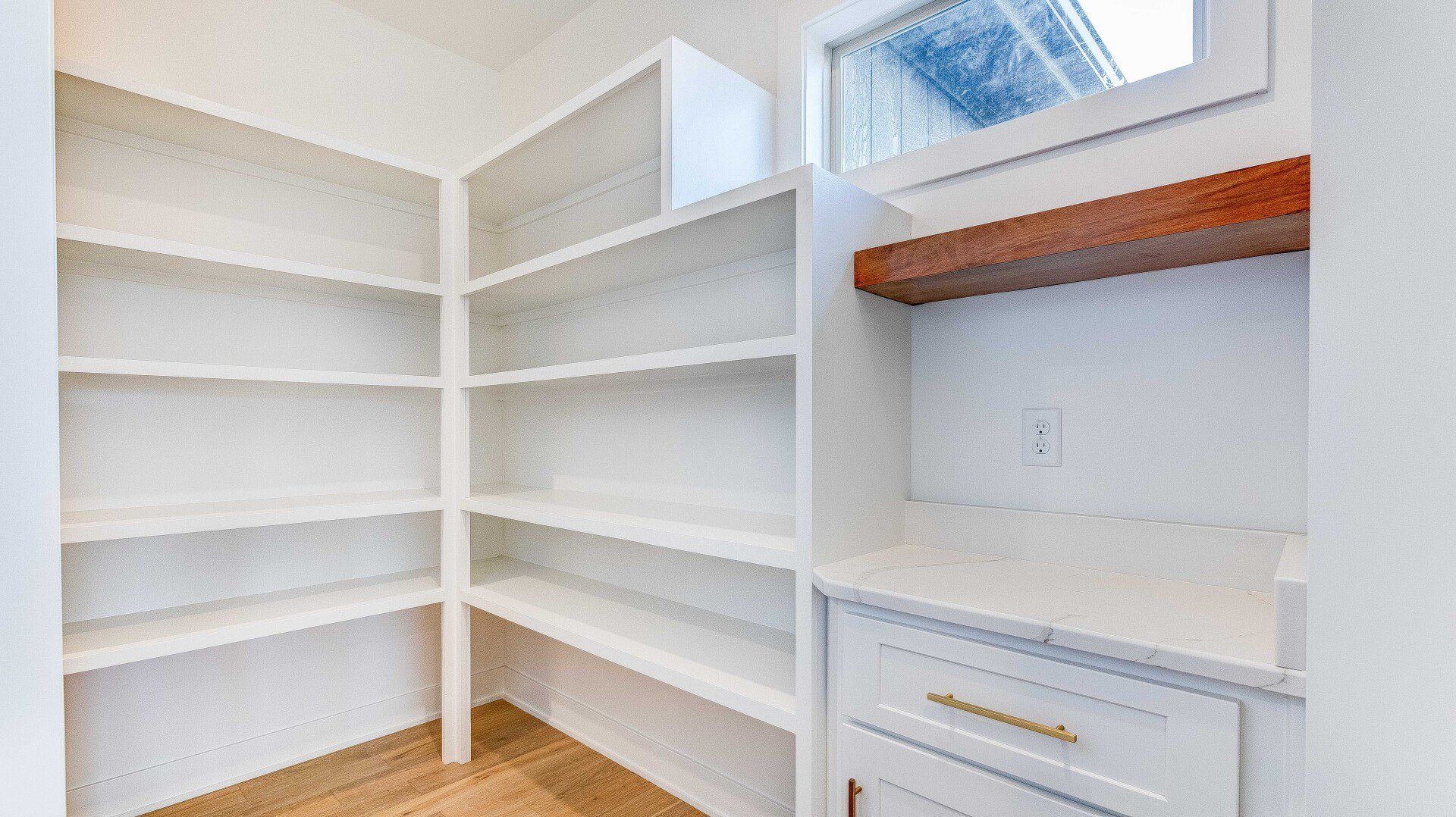 A pantry with lots of shelves and a window.