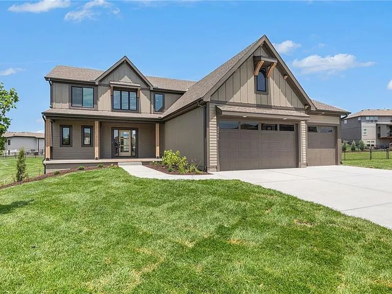A large house with a garage and a large lawn in front of it.