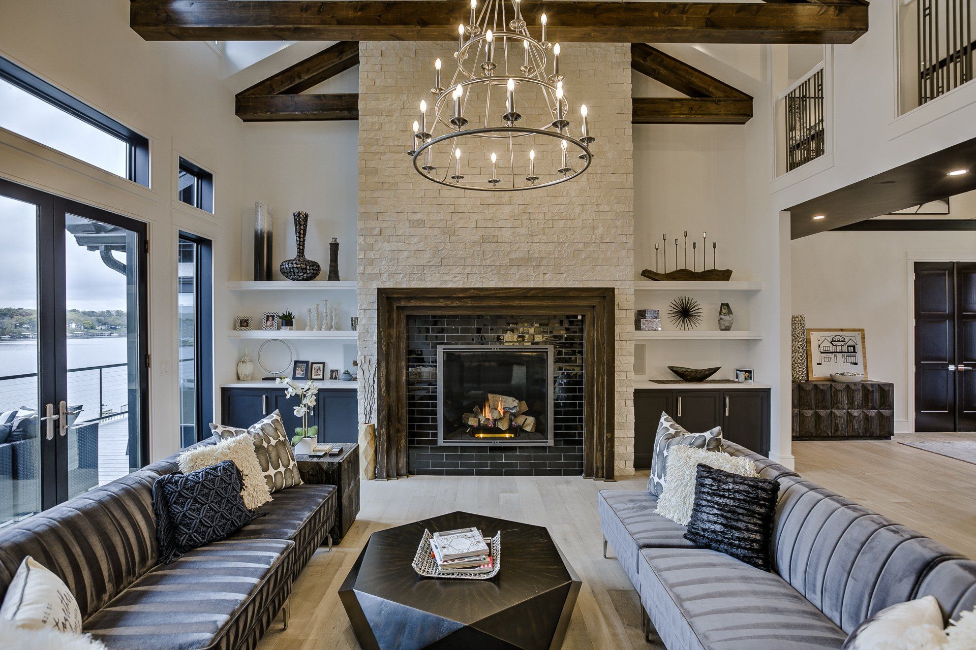 A living room with a fireplace , couch , coffee table and chandelier.