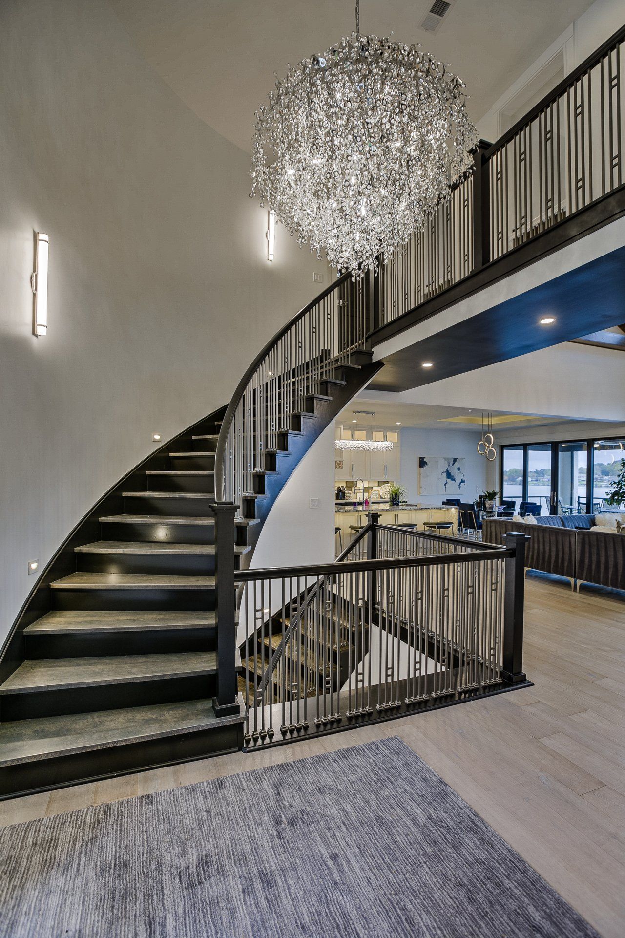 A spiral staircase in a house with a chandelier hanging from the ceiling.