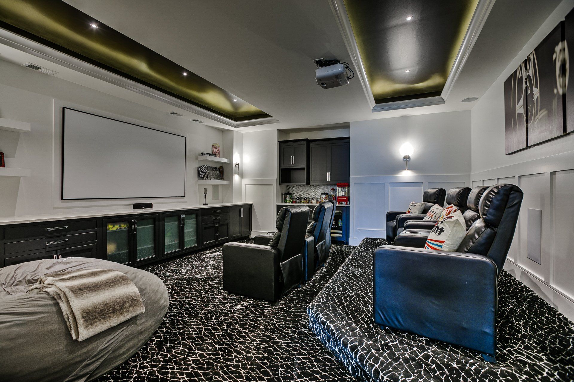 A home theater with a projector screen , chairs , and a couch.