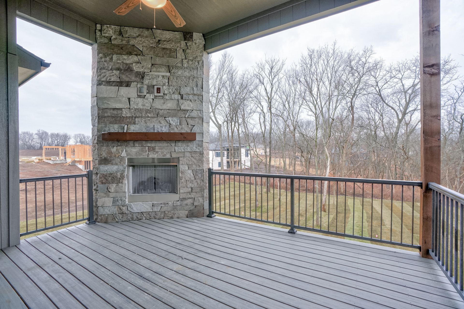A large deck with a fireplace and a ceiling fan.