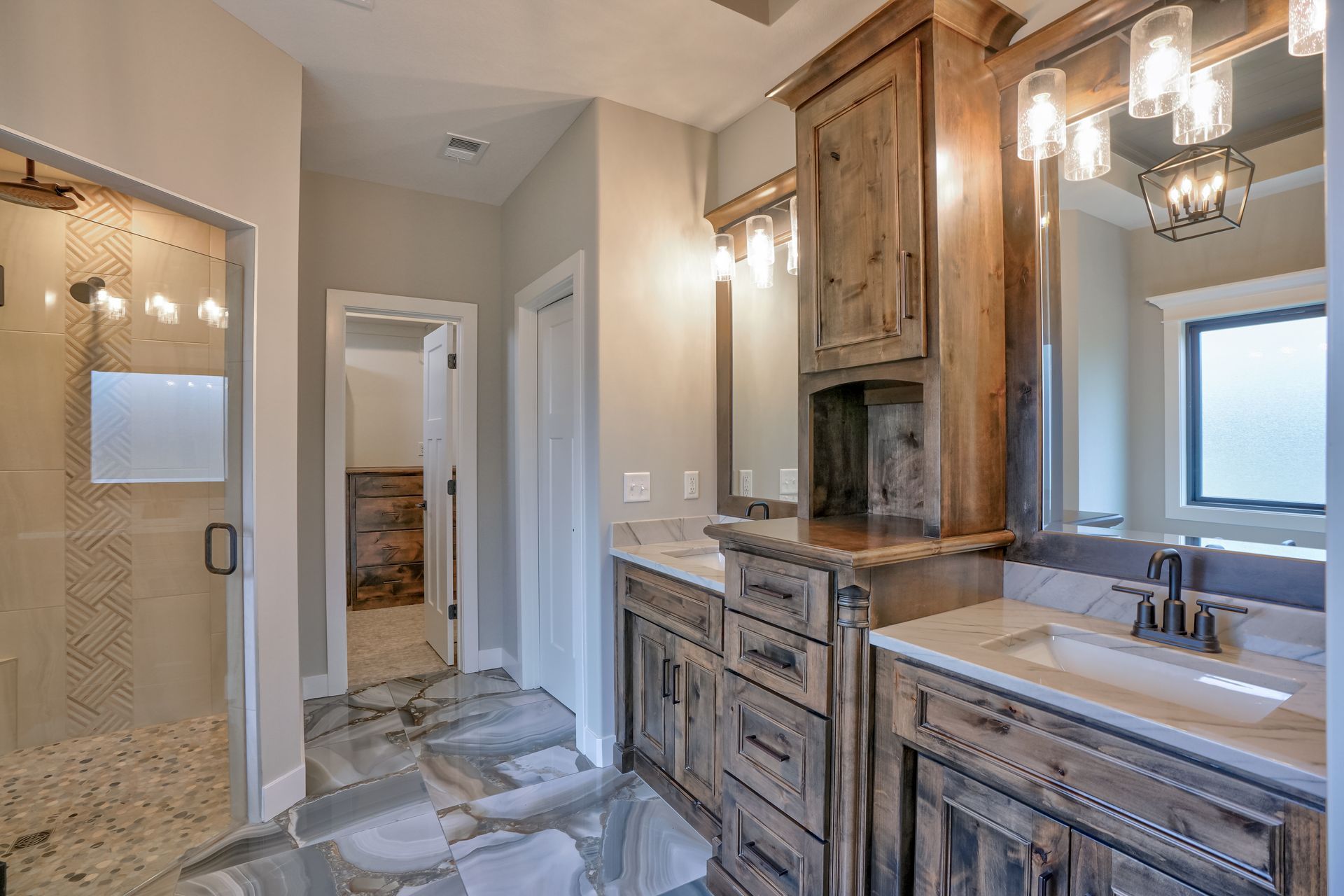 A bathroom with two sinks , a mirror and a walk in shower.