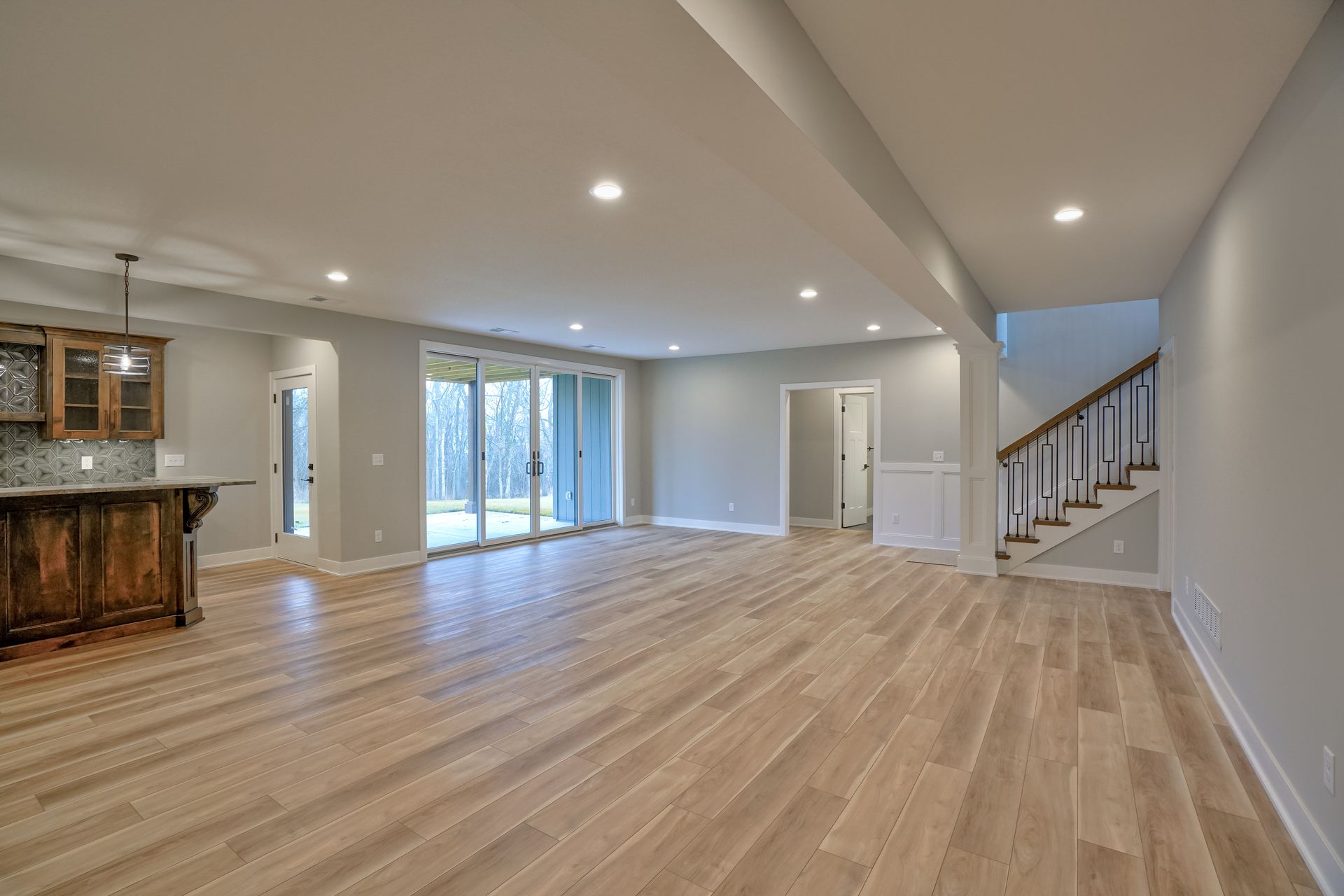 A large empty basement with hardwood floors and stairs.