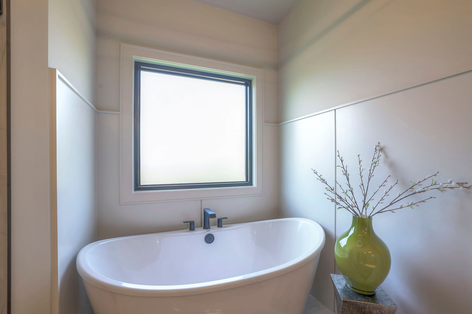 A bathroom with a bathtub and a vase of flowers.