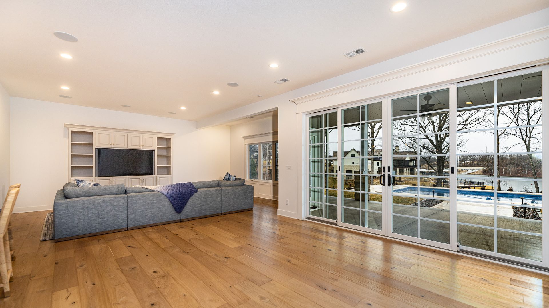 A living room with a couch , television , and sliding glass doors leading to a pool.