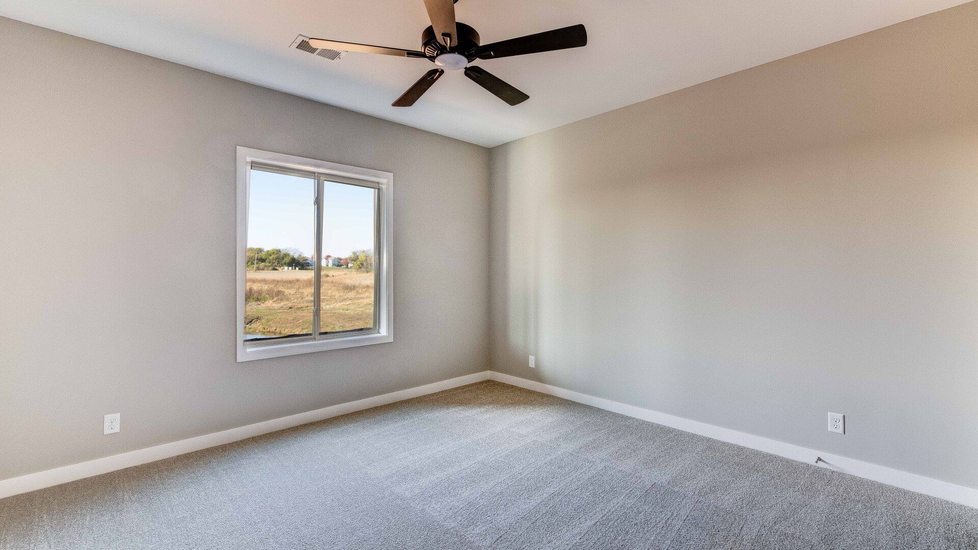 An empty bedroom with a ceiling fan and a window.