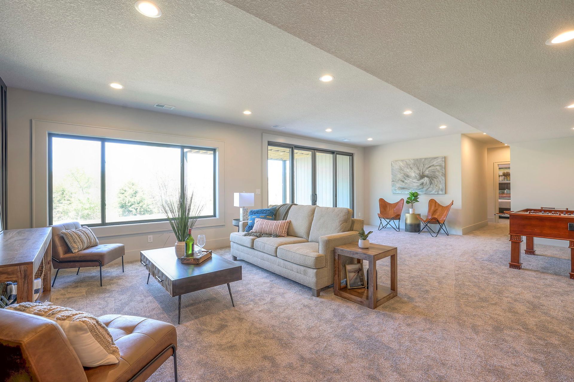 A living room with a couch , chairs , a table and a pool table.