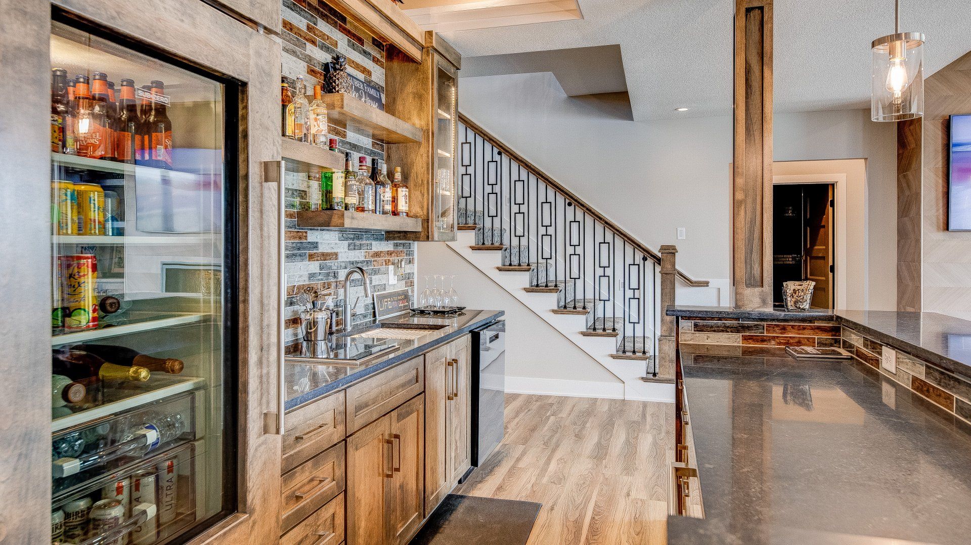 A kitchen with a refrigerator and a staircase in the background.