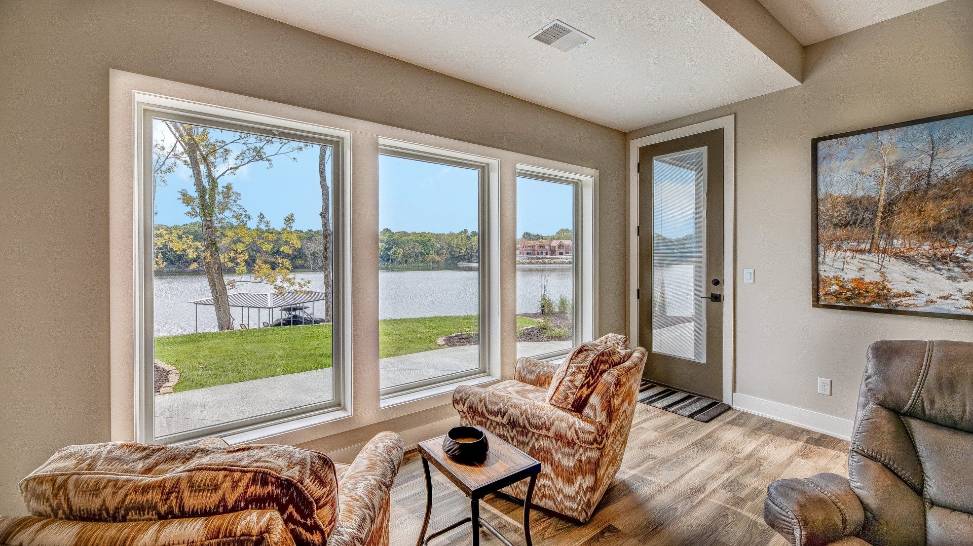 A living room with a lot of windows overlooking a lake.