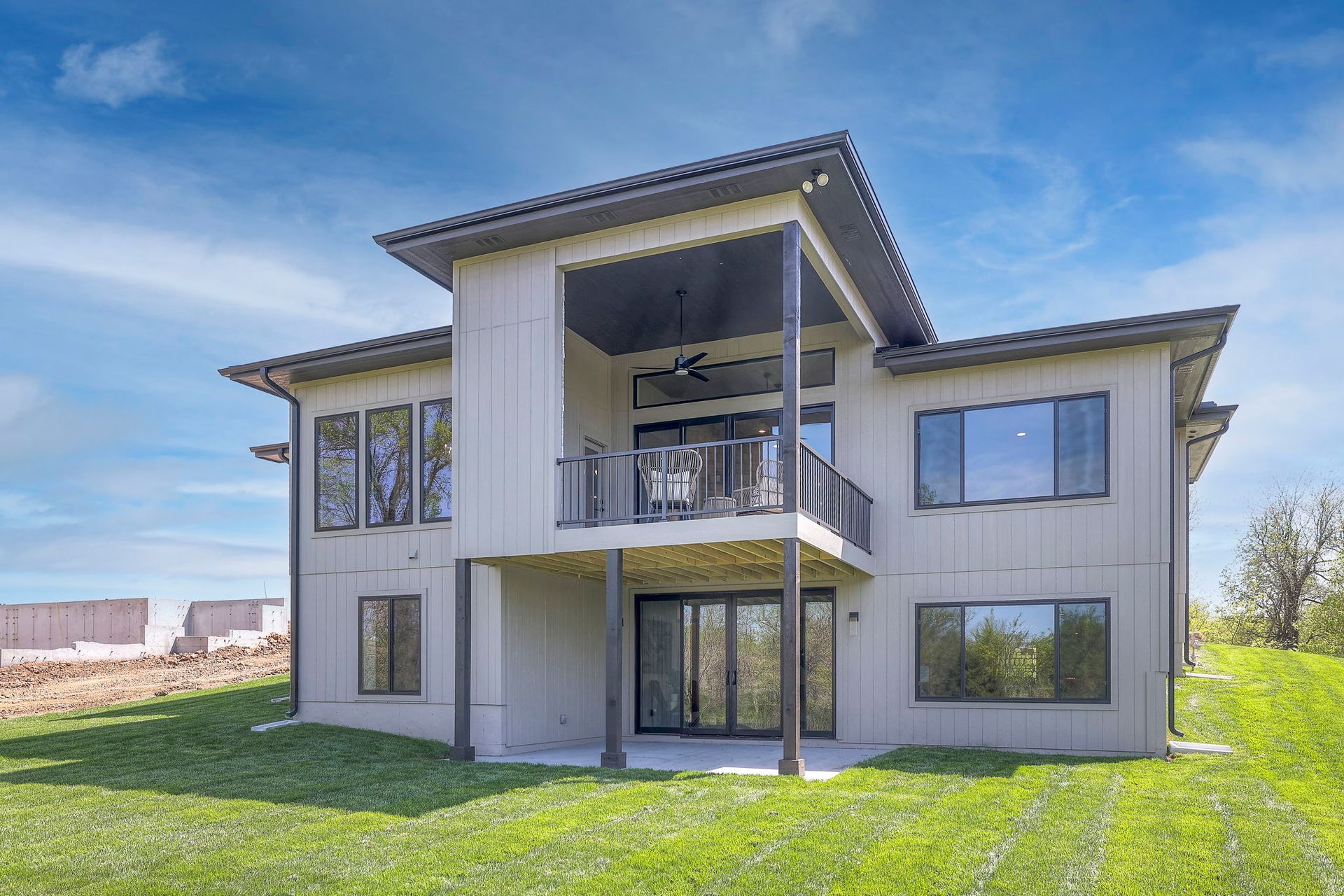 A large house with a balcony is sitting on top of a lush green hill.