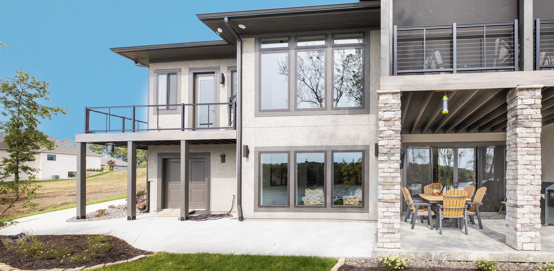 A large house with a lot of windows and a patio with a table and chairs.