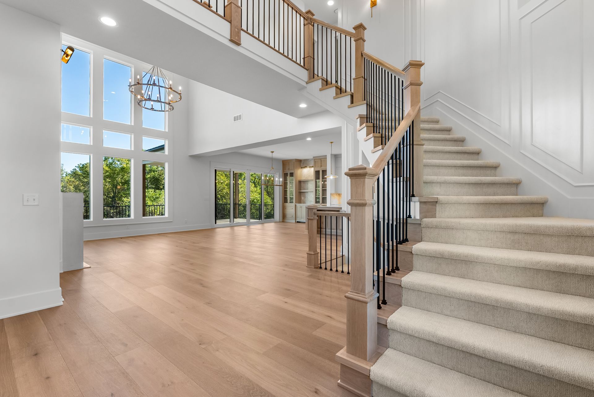 Spacious home interior with wooden floors, grand staircase, large windows, and natural light.