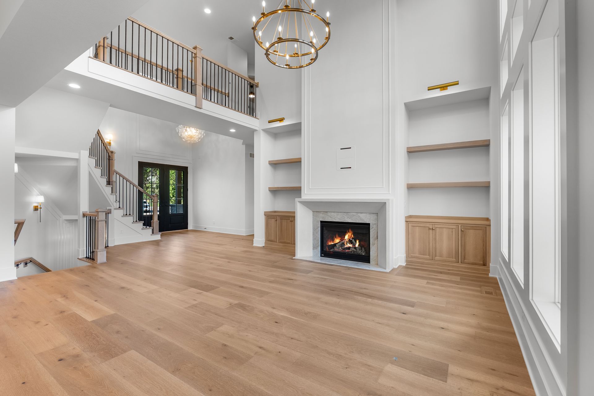 Spacious living room with fireplace, built-in shelves, hardwood floors, and a second-floor balcony.
