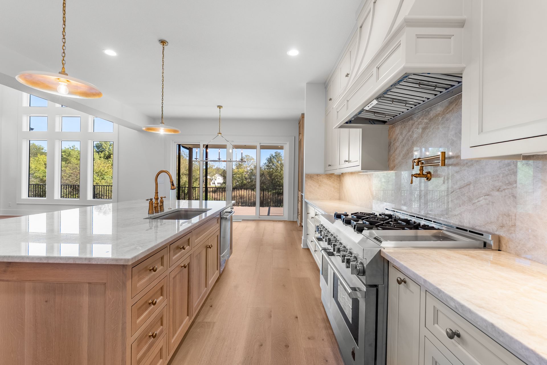 Spacious kitchen with a large island, wood cabinets, stainless steel appliances, and outdoor access.