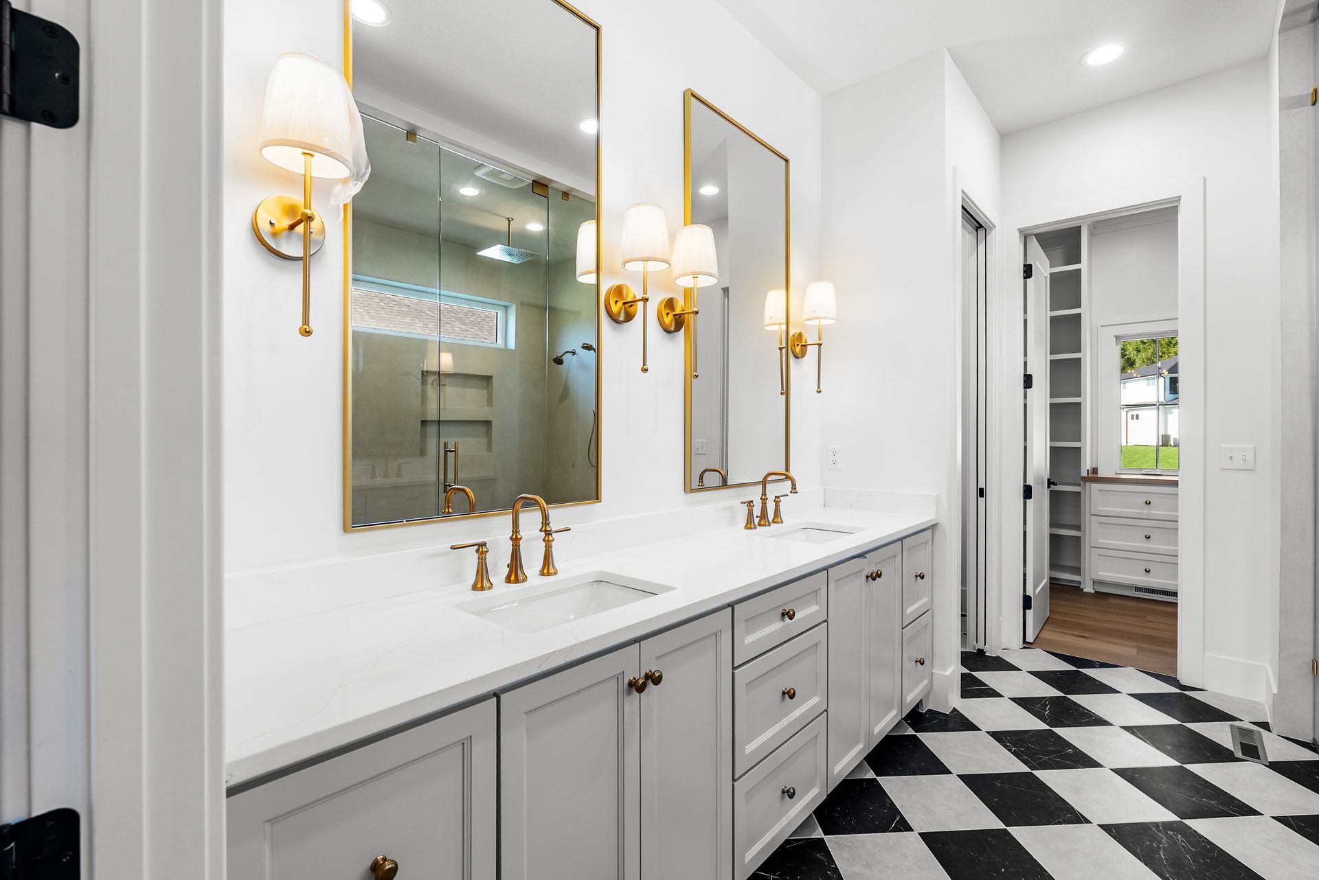 Bathroom with white cabinets, gold fixtures, black and white checkered floor, and a walk-in closet.