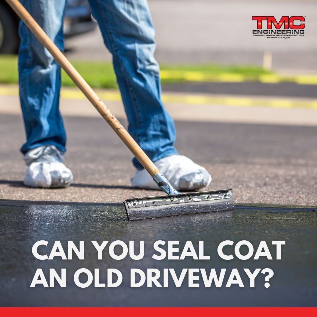 A person is using a mop to seal an old driveway
