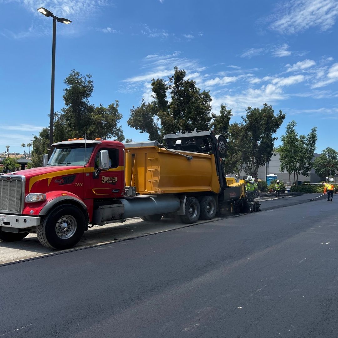 A red and yellow dump truck is parked on the side of the road
